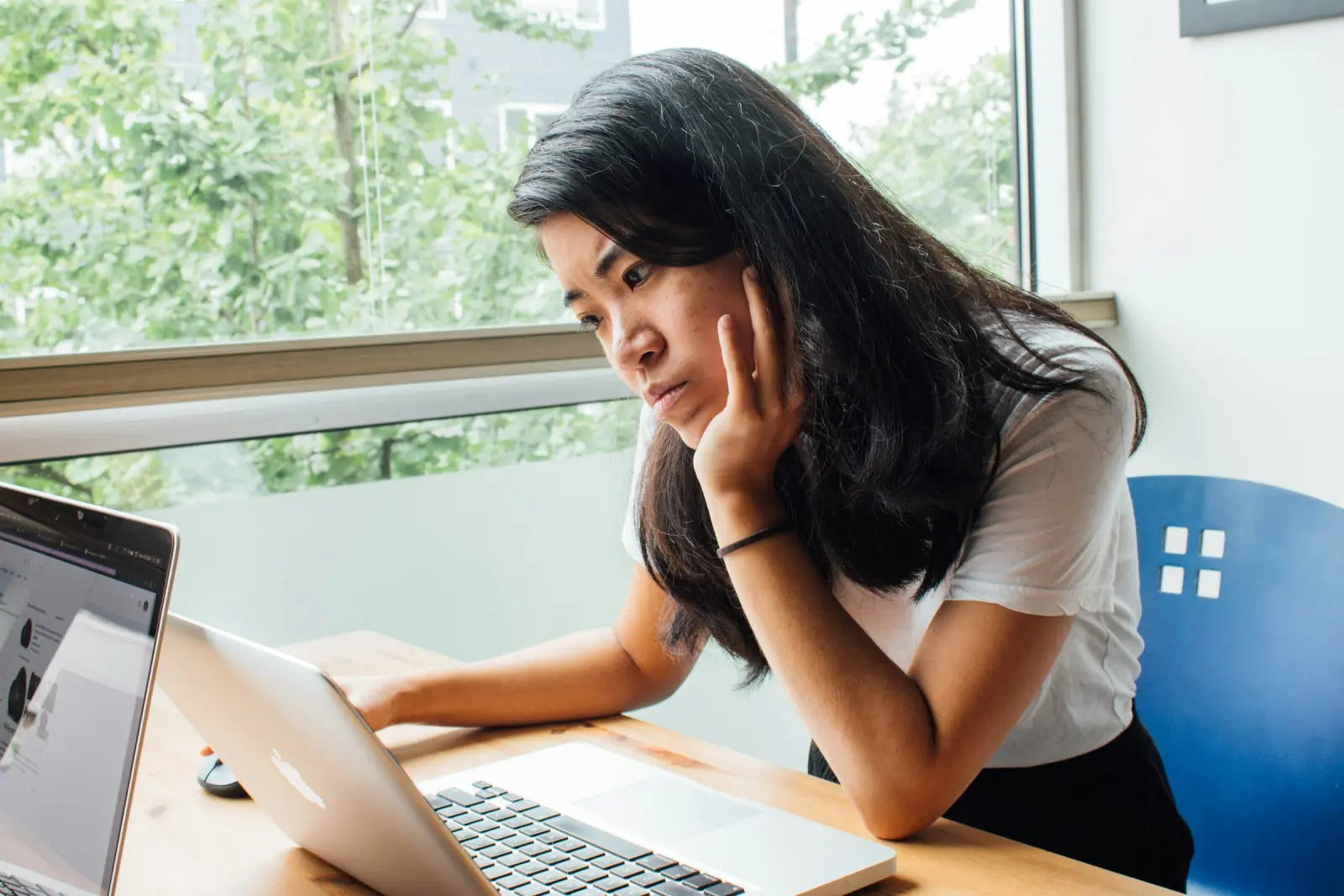 A woman leaning on her desk, frowning at her laptop