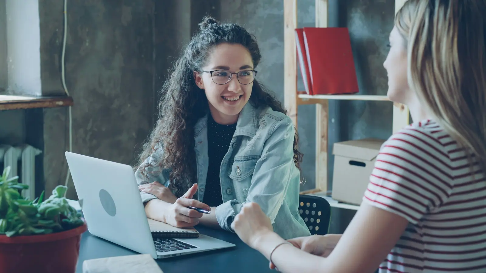 Two women having a friendly discussion over a laptop